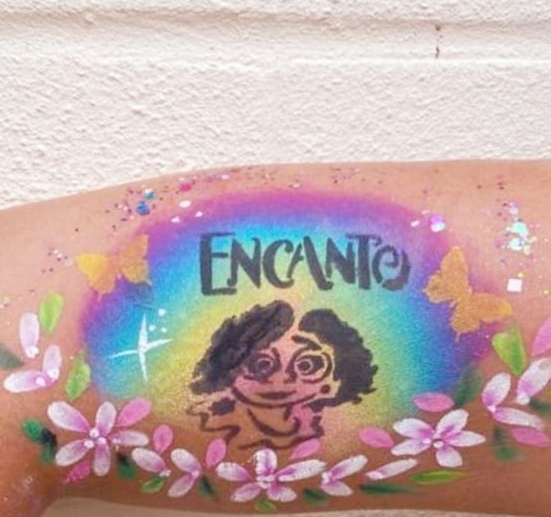 Encanto-themed rainbow arm painting with flowers and butterflies